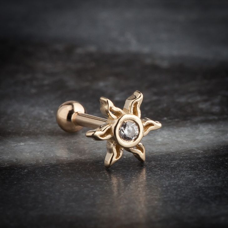 14K yellow gold sunburst helix stud with CZ, styled on dark stone surface showing handcrafted detail