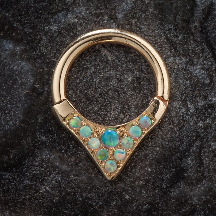 14K yellow gold opal clicker ring with V-shaped setting, displayed on dark stone surface
