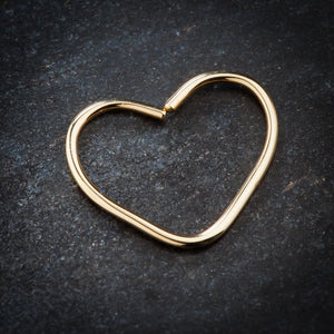 14K yellow gold heart seam ring laid flat on dark stone surface showing texture and scale