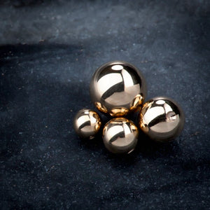 Four 14K gold replacement balls in multiple sizes grouped together showing size comparison