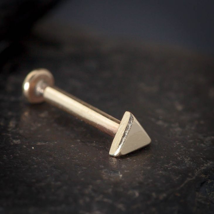14k rose gold tiny triangle cartilage stud on dark stone surface, showing post and flat back detail