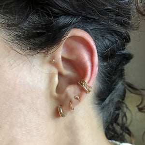 14k gold band ear cuff worn on model's ear, stacked with twisted and plain gold cuffs