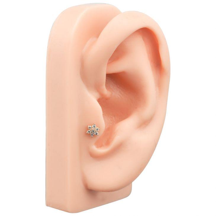 CZ flower flat back labret stud worn in tragus piercing on silicone ear display, side angle view