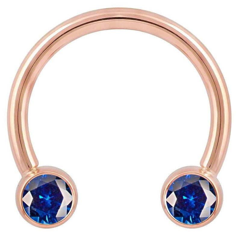14k rose gold circular barbell with deep blue CZ bezel ends, front view showing warm pink-gold tone