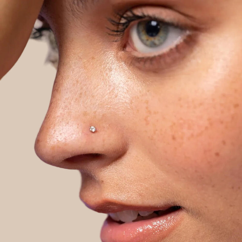 2mm diamond gold flat back stud worn in a nose piercing on a model, showing dainty fit