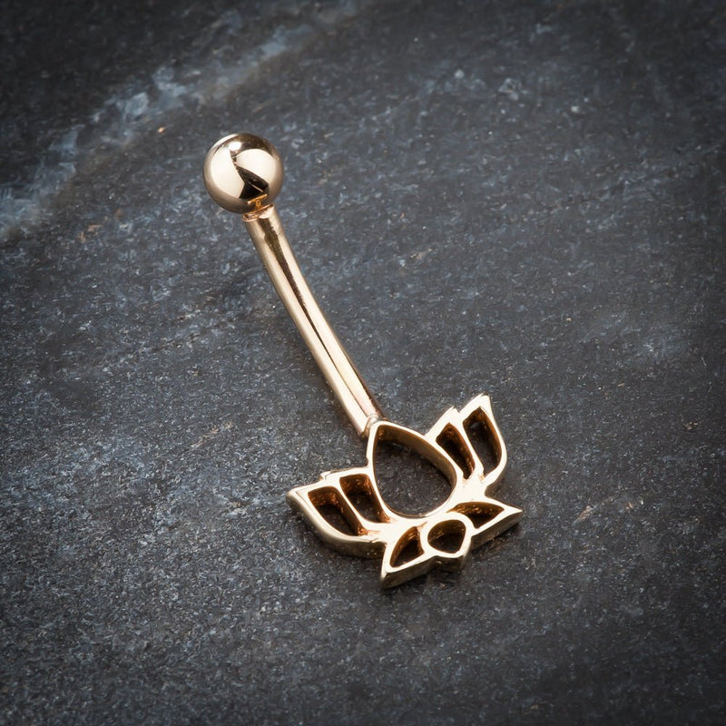14k rose gold lotus flower belly ring angled on dark stone surface showing charm detail