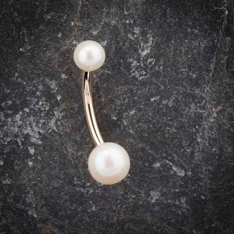14k yellow gold cultured pearl navel ring with lustrous white pearls on dark granite background