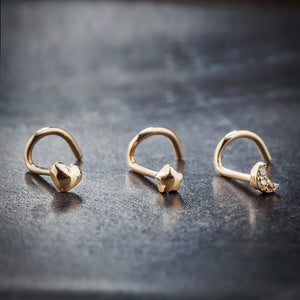 Three 14K yellow gold nose rings side by side: puffy heart, puffy star, and crescent moon styles