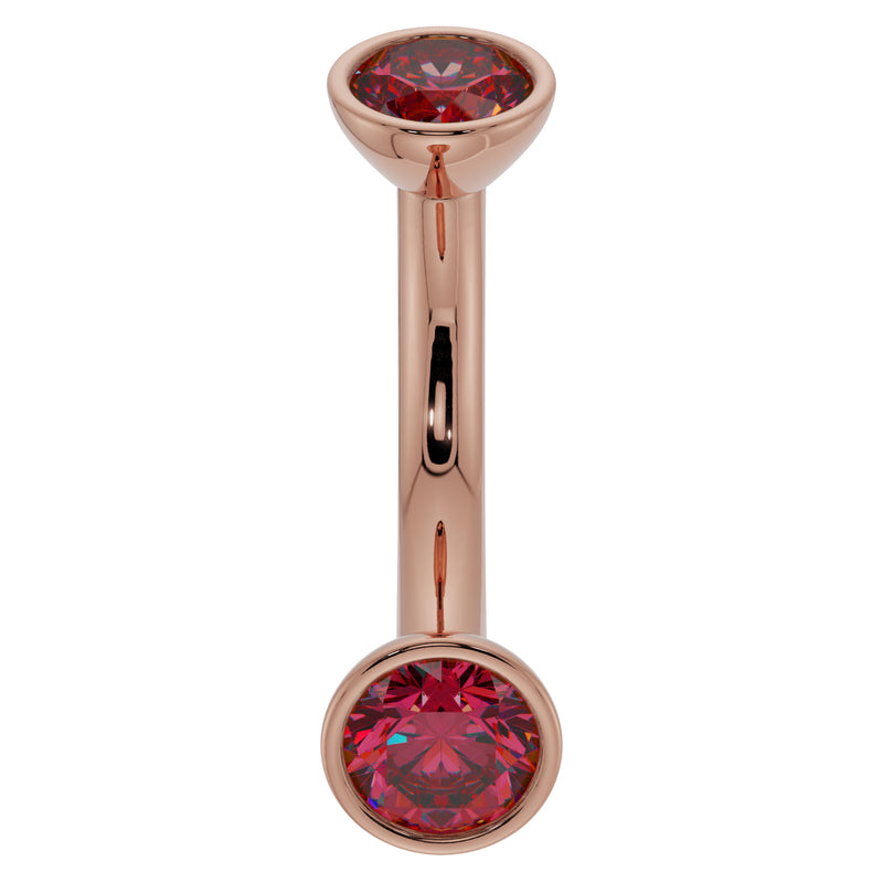 14k rose gold 14G ruby curved barbell with larger bezel-set ruby ends, angled front view