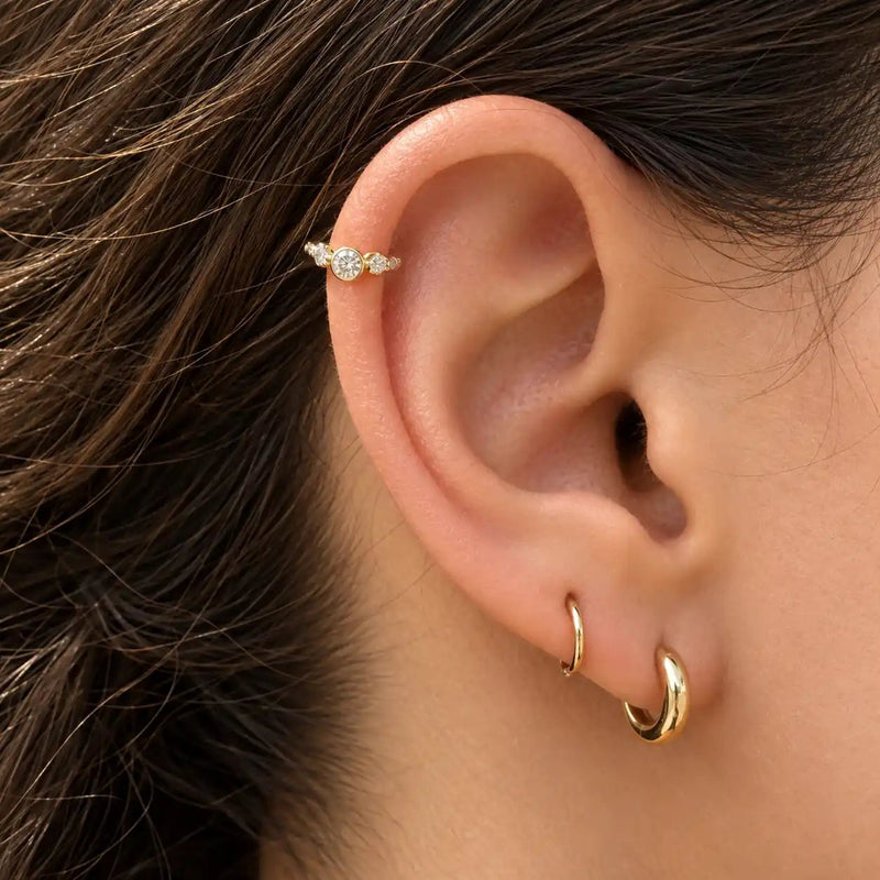 14k gold three-CZ clicker ring worn in helix piercing on model, showing snug fit and sparkle