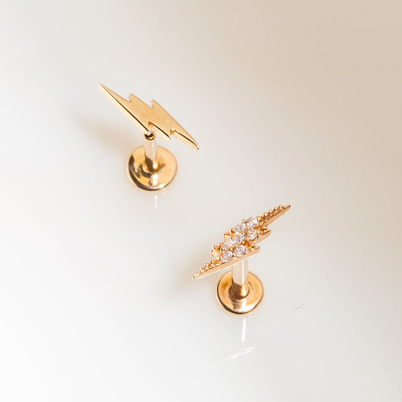 Two 14k gold lightning bolt flat back studs side by side — plain and CZ-set versions compared for style