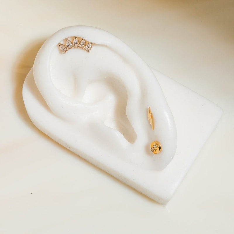 14k gold white sapphire crescent cartilage stud on helix of white ceramic ear display model
