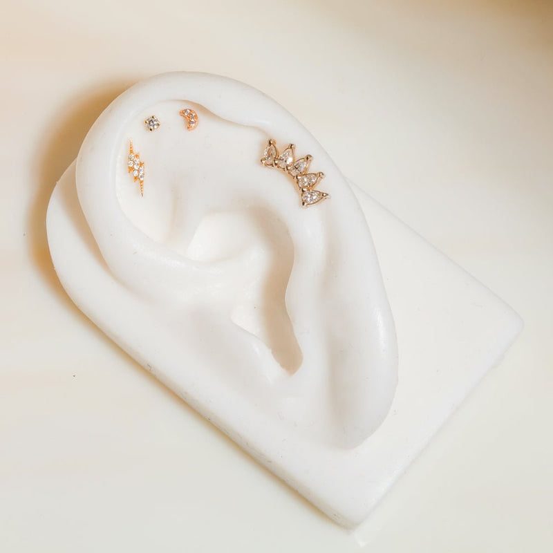 Diamond pavé lightning bolt cartilage stud on white ear display with mixed gold piercing jewelry