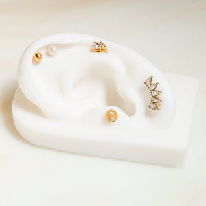 14K gold ball labret stud styled on white ear display with other cartilage jewelry for placement ideas