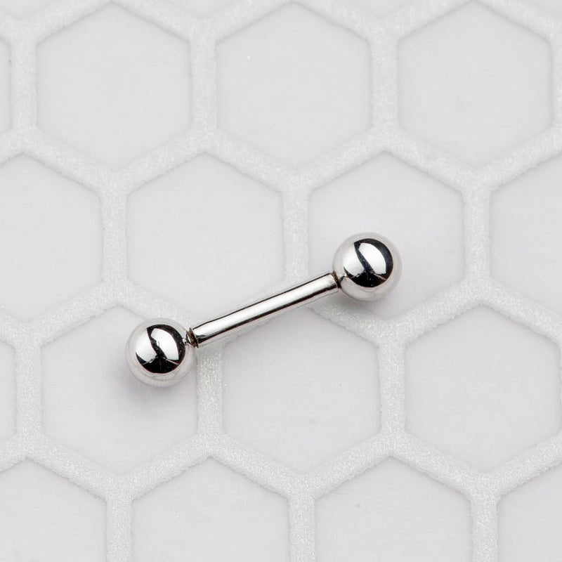 Small 14k white gold straight barbell on hexagon tile surface showing size reference for short length