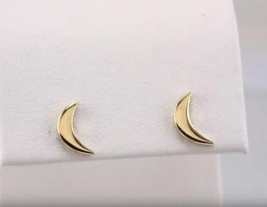 Pair of 14k yellow gold crescent moon studs displayed on white jewelry cushion, front-facing view