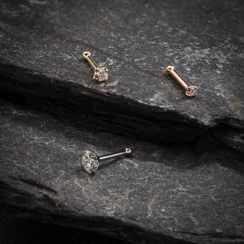 14k gold CZ nose bone and straight post styles in yellow, white, and rose gold on slate background