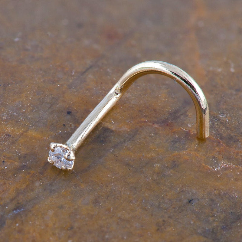 14k yellow gold CZ nose ring twist style resting on stone surface, showing warm gold tone
