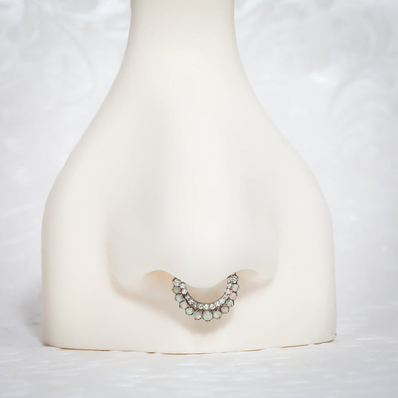Opal and diamond moon clicker hoop shown in a septum piercing on a nose mannequin for fit reference