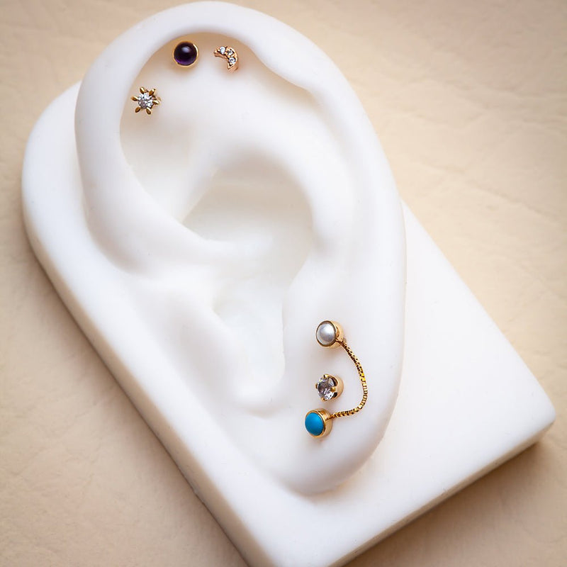 Amethyst cabochon flat back stud styled in upper cartilage piercing on white ear display