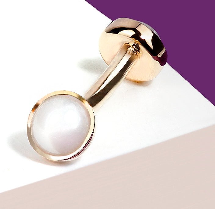 Angled close-up of 14k rose gold pearl bezel curved barbell showing bezel setting detail