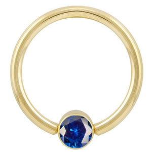 14k yellow gold fixed bead ring with blue CZ bezel, angled front view showing stone detail