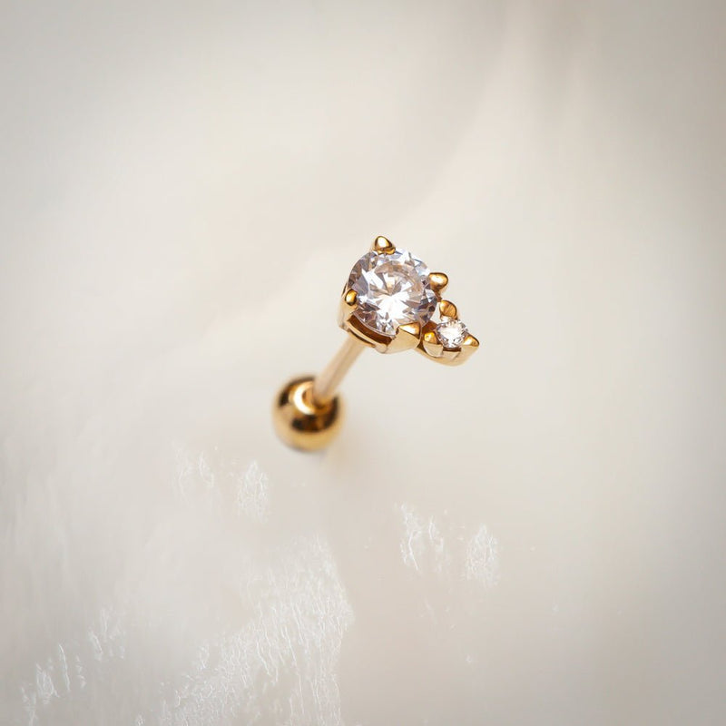 14k yellow gold CZ cartilage stud earring resting on soft white textured surface