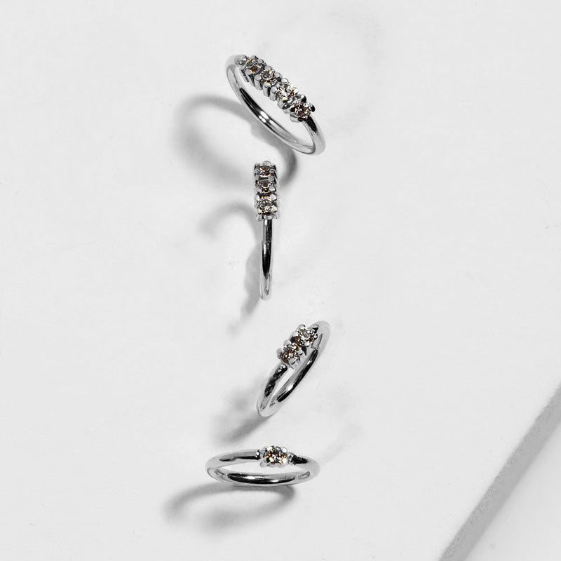 14k white gold three-diamond seam rings in multiple sizes arranged on white surface