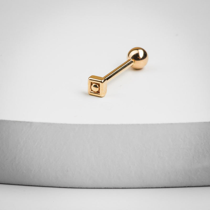 14k rose gold square cartilage barbell resting on a white surface, showing full barbell length and scale