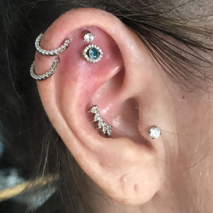 Diamond pave clicker rings stacked in a helix ear piercing alongside other crystal jewelry