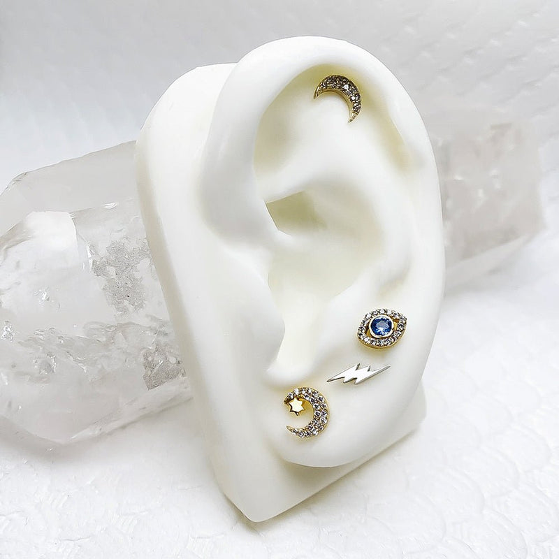 Gold diamond moon and star labret stud displayed on white ear mannequin with crystal backdrop