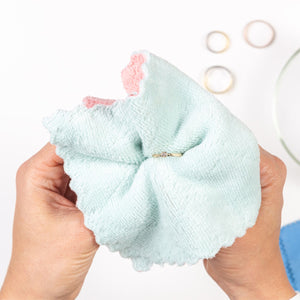 Hands polishing a gold ring with a soft cloth, jewelry rings blurred in background, FreshTrends Restore Service