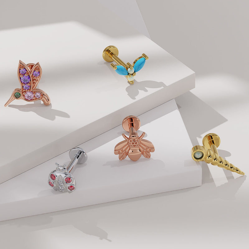 Hummingbird flat back earring in rose gold displayed alongside bee, ladybug, and other nature-themed labrets