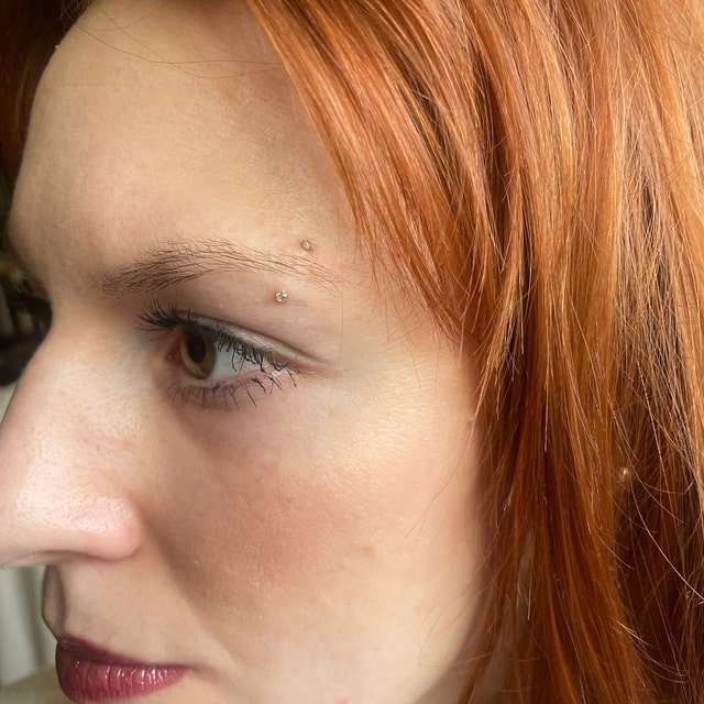 Dainty CZ curved barbell shown in an eyebrow piercing on a model for fit and scale reference