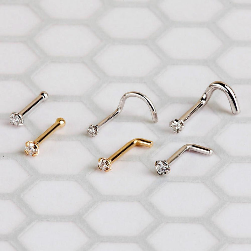 Diamond nose studs in gold and silver shown in multiple backing styles arranged on white tile surface