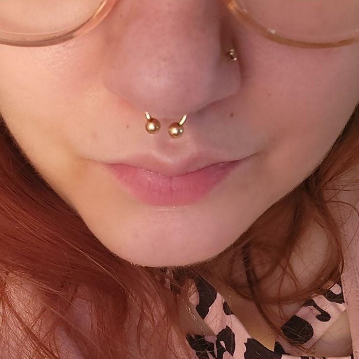 14k gold circular barbell shown in a septum piercing, close-up fit view on model