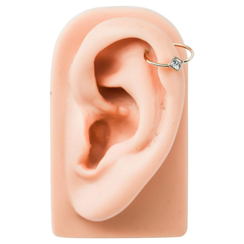 14k gold princess-cut CZ fixed bead ring worn in helix cartilage piercing on ear model