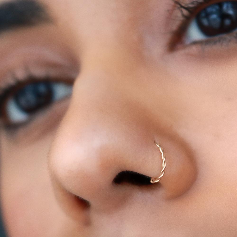 Model wearing twisted seamless ring in nose piercing