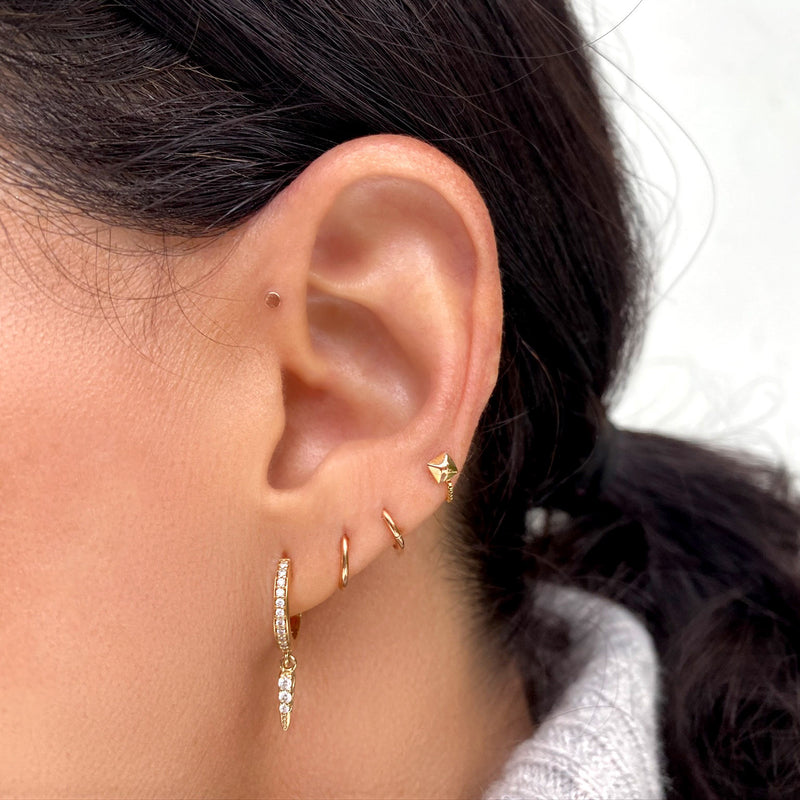 Tiny 14K gold disc flat back stud in helix piercing, shown in curated ear with gold hoops
