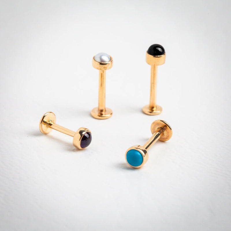 14k gold flat back labrets in pearl, black, amethyst, and turquoise cabochon shown side by side for comparison