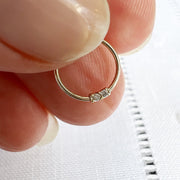 14K yellow gold two-diamond seam ring held between fingers for size reference