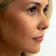 Close-up of 2mm diamond perlage nose stud worn in piercing, showing delicate milgrain bezel on skin