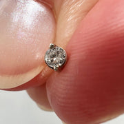 Duo-prong VS1 diamond threadless stud end held between fingers to show tiny actual size
