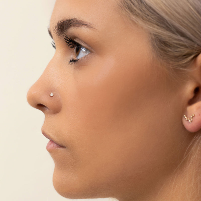2.5mm diamond flat back stud worn in nostril piercing, side profile showing dainty flush fit on model