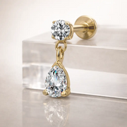 14k yellow gold diamond pear drop labret resting on clear acrylic block, angled side view showing flat back post