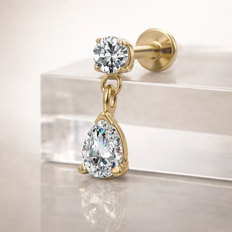 14k yellow gold diamond pear drop labret resting on clear acrylic block, angled side view showing flat back post