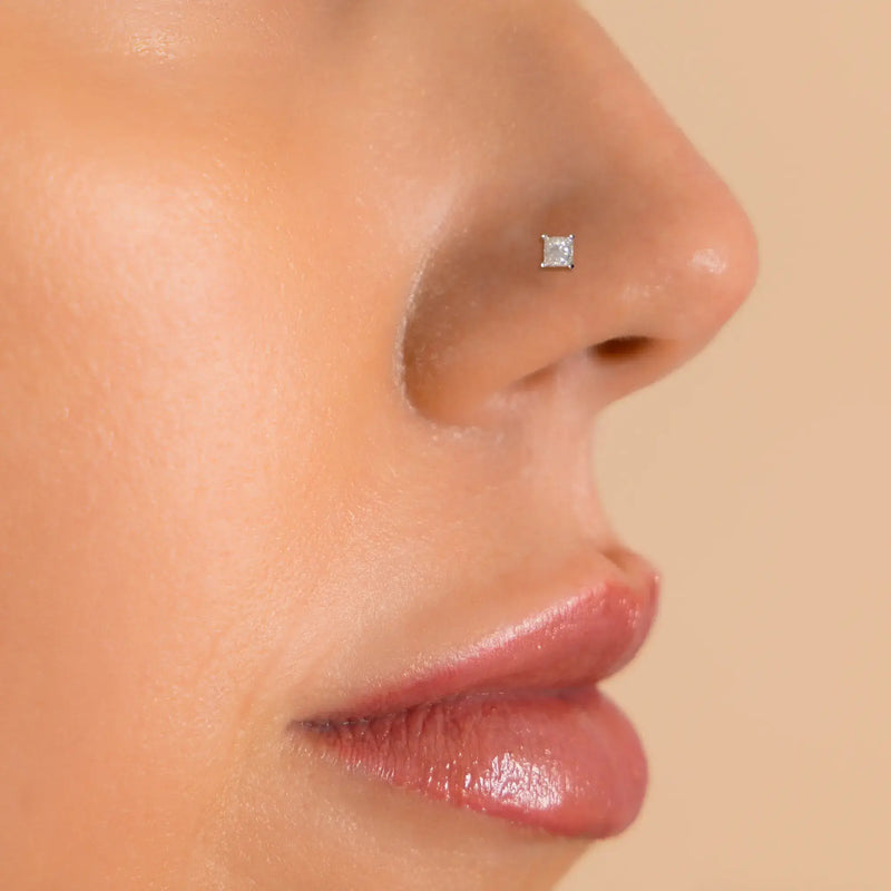 2.5mm princess-cut diamond nose ring shown in pierced nose on model for fit and scale reference
