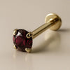 14K yellow gold garnet labret with 4-prong setting and flat disc backing, angled studio view