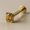14K yellow gold citrine flat back labret with 4-prong setting, angled studio shot on beige background
