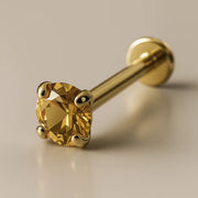 14K yellow gold citrine flat back labret with 4-prong setting, angled studio shot on beige background